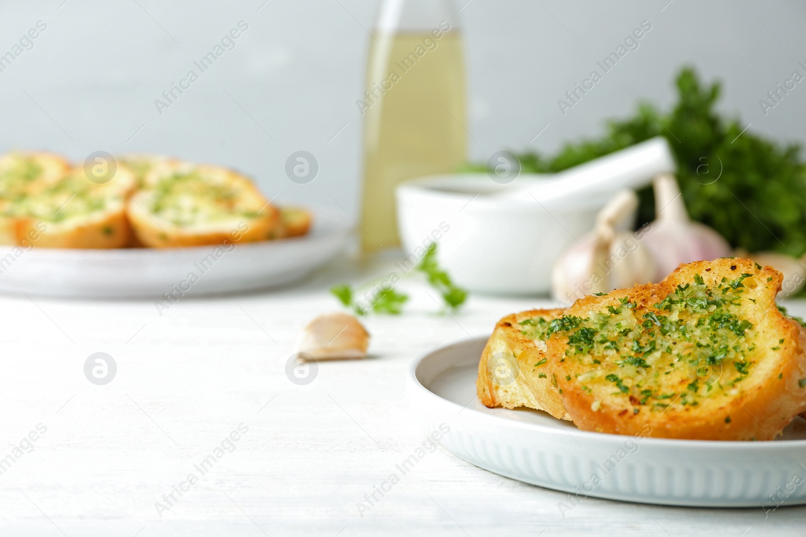 Photo of Slices of toasted bread with garlic and herbs on white wooden table. Space for text