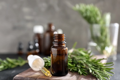 Photo of Bottle of rosemary essential oil on wooden board