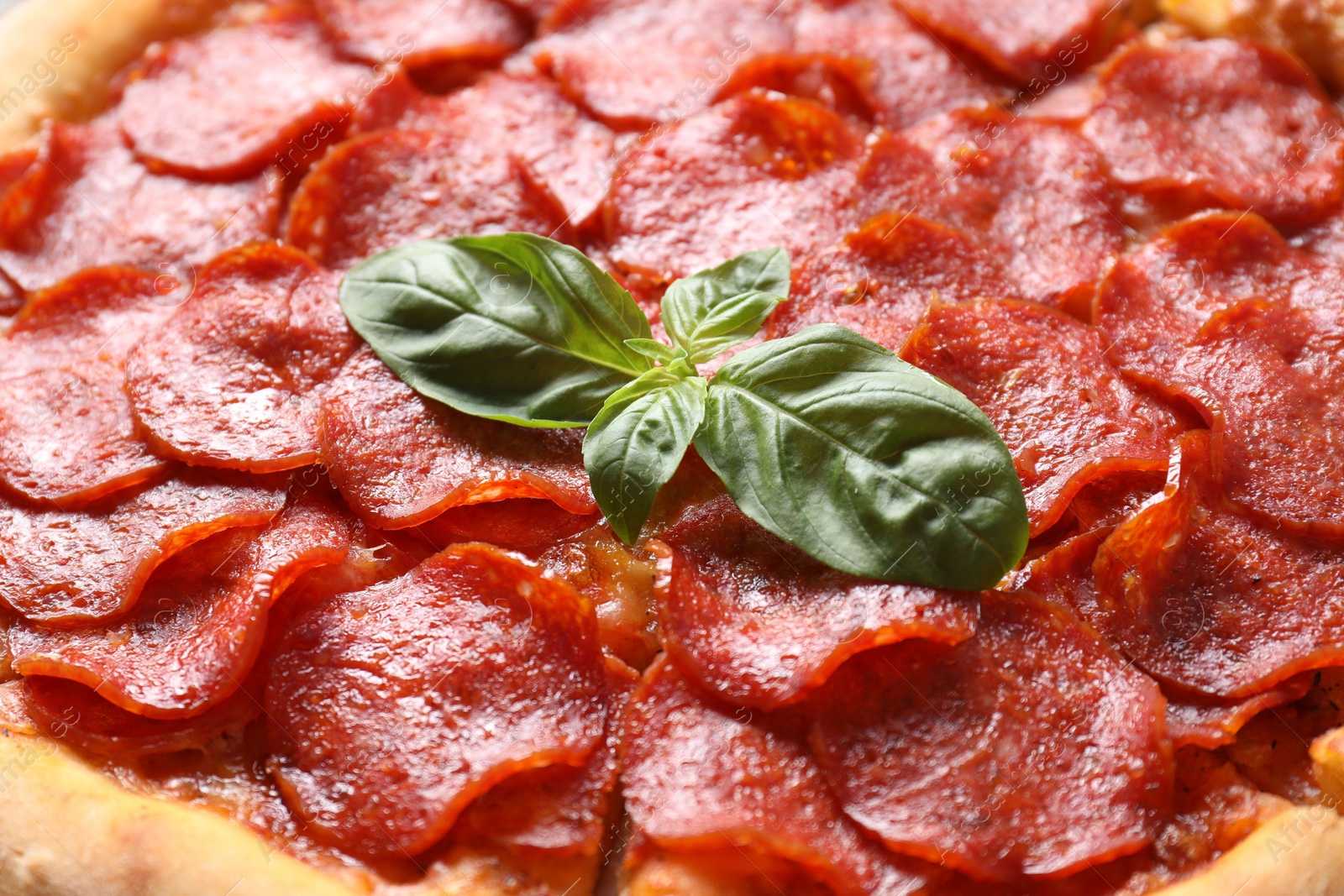 Photo of Tasty pepperoni pizza with basil as background, closeup