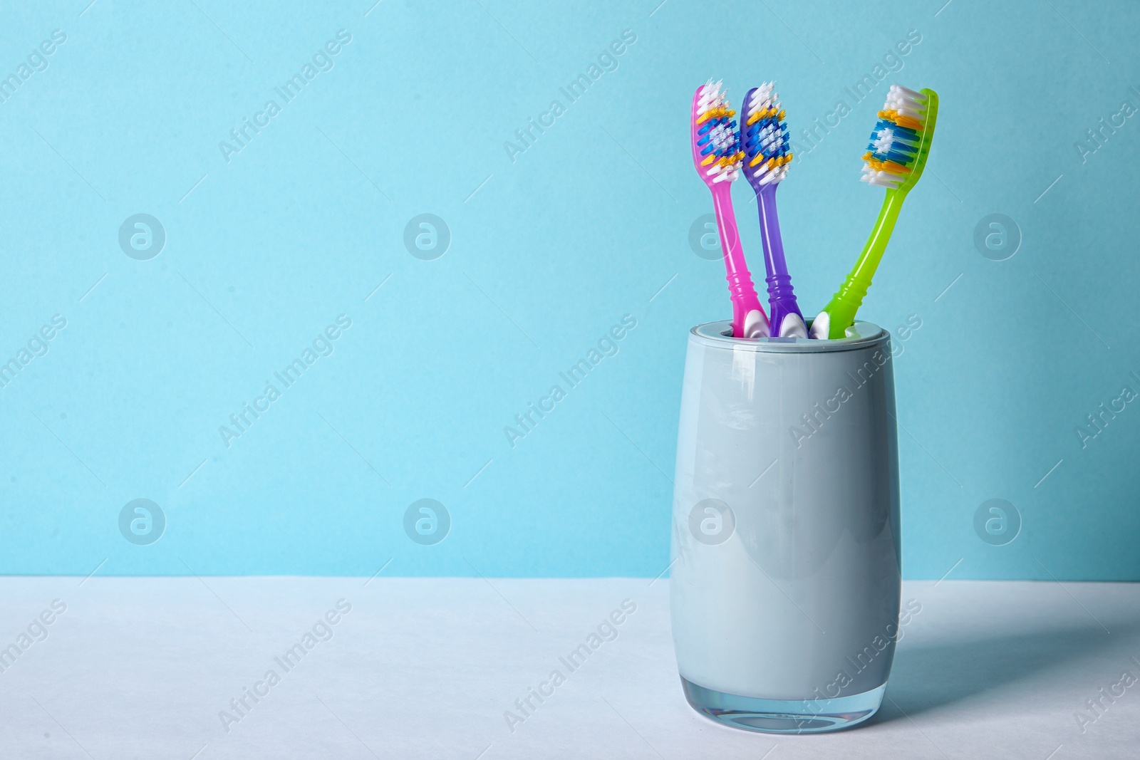 Photo of Cup with toothbrushes on table against color background. Dental care