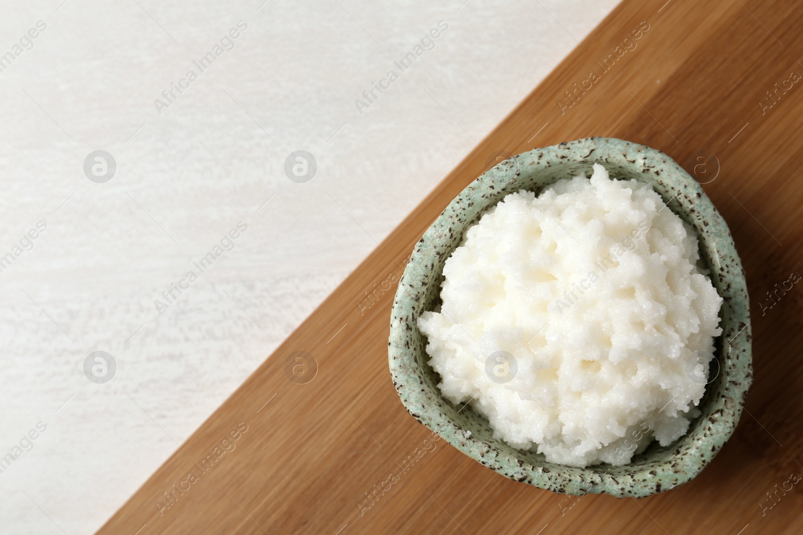 Photo of Shea butter in bowl on wooden board, top view. Space for text