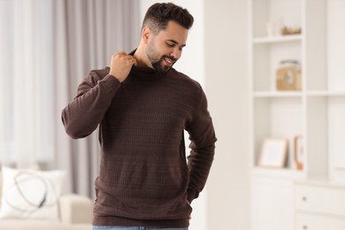 Happy man in stylish sweater at home, space for text