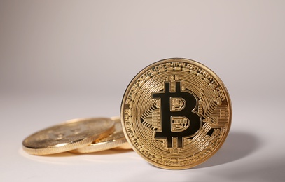 Photo of Shiny gold bitcoins on light background, space for text. Digital currency