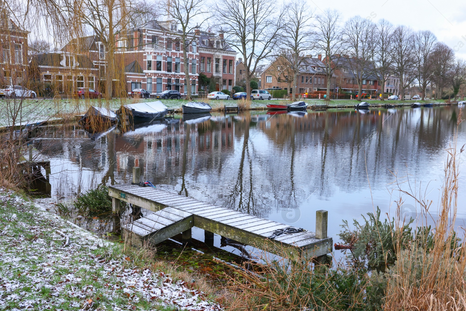 Photo of Picturesque view of water canal with moored boats in city on winter day