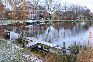 Picturesque view of water canal with moored boats in city on winter day