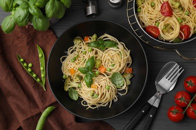 Delicious pasta primavera with basil, broccoli and peas served on grey wooden table, flat lay