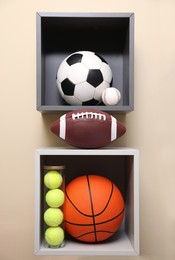 Photo of Shelves with different sport balls on beige wall indoors