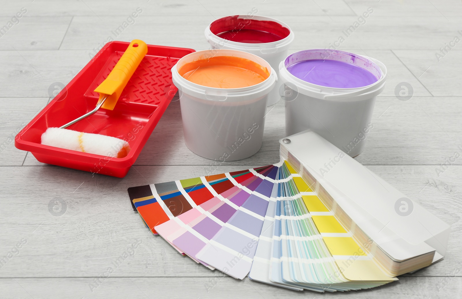 Photo of Buckets of paints, palette and decorator's tools on light wooden background