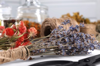 Photo of Bunches of dry flowers on white wooden table, closeup