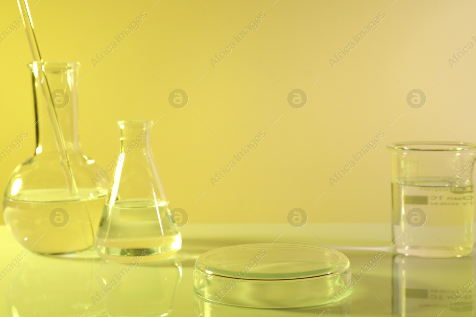 Photo of Laboratory analysis. Different glassware on table against yellow background