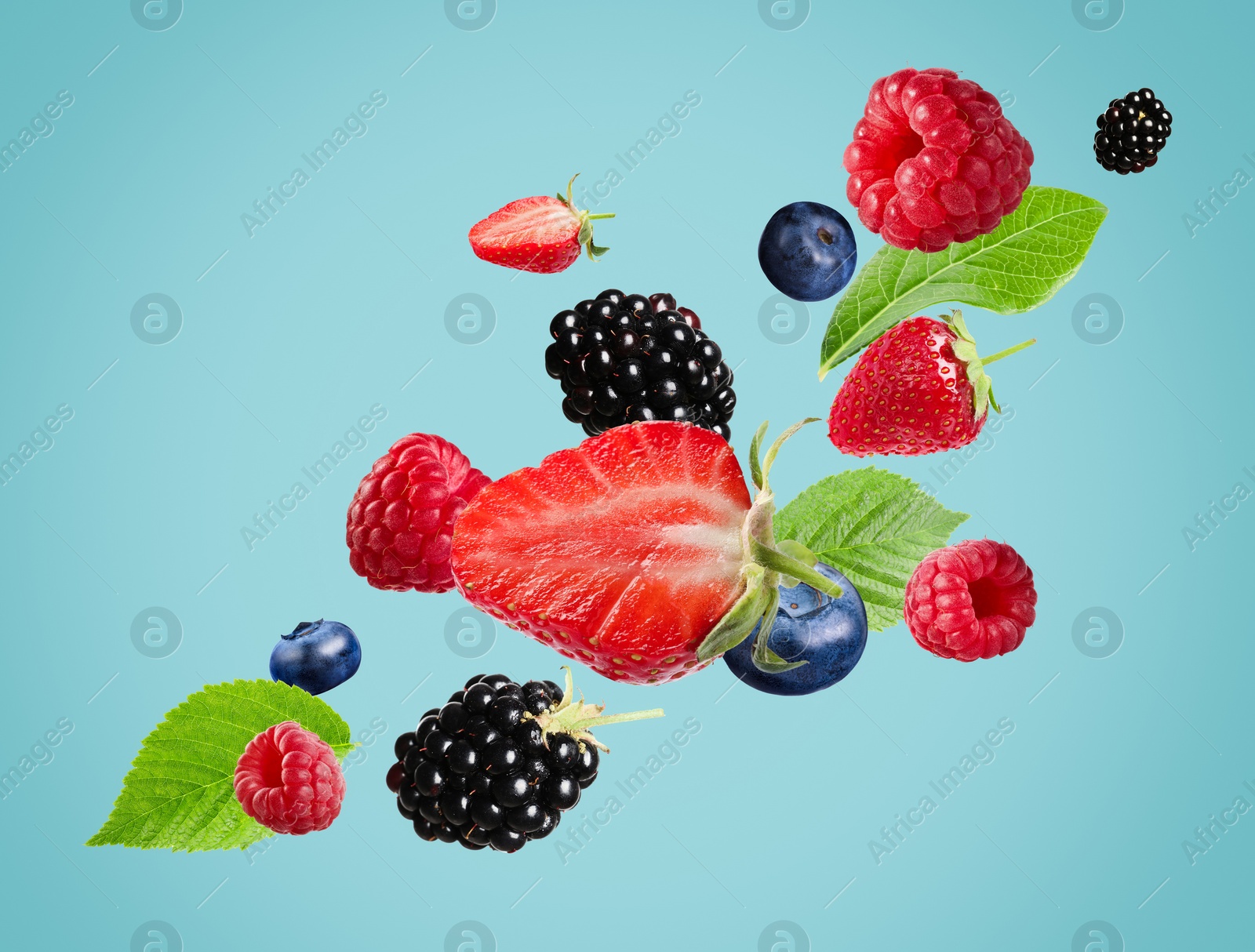 Image of Many different fresh berries falling on light blue background