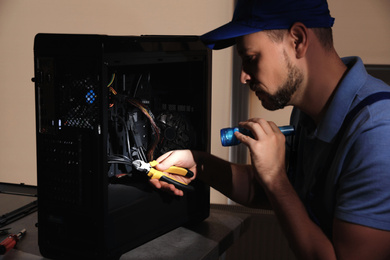 Repairman with flashlight fixing system unit indoors