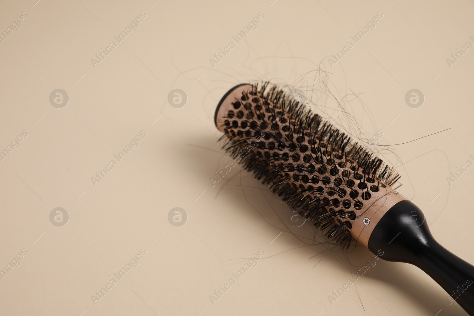 Photo of Professional brush with lost hair on beige background, closeup. Space for text