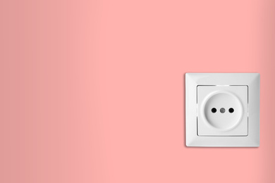 Image of Pink wall with power socket, space for text. Electrical supply