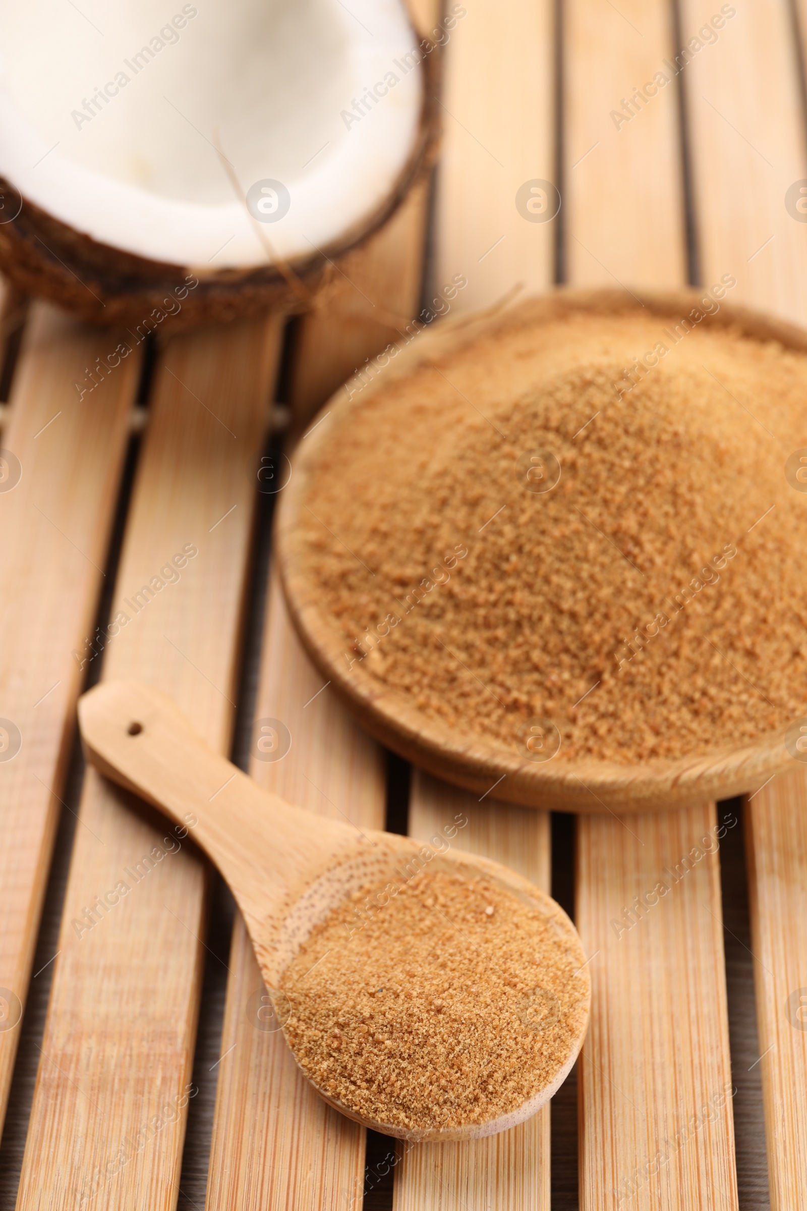 Photo of Coconut sugar, spoon, plate and fruit on wooden table, closeup