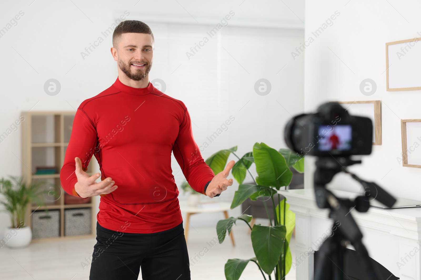 Photo of Trainer recording fitness lesson on camera at home