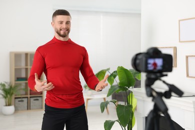 Photo of Trainer recording fitness lesson on camera at home
