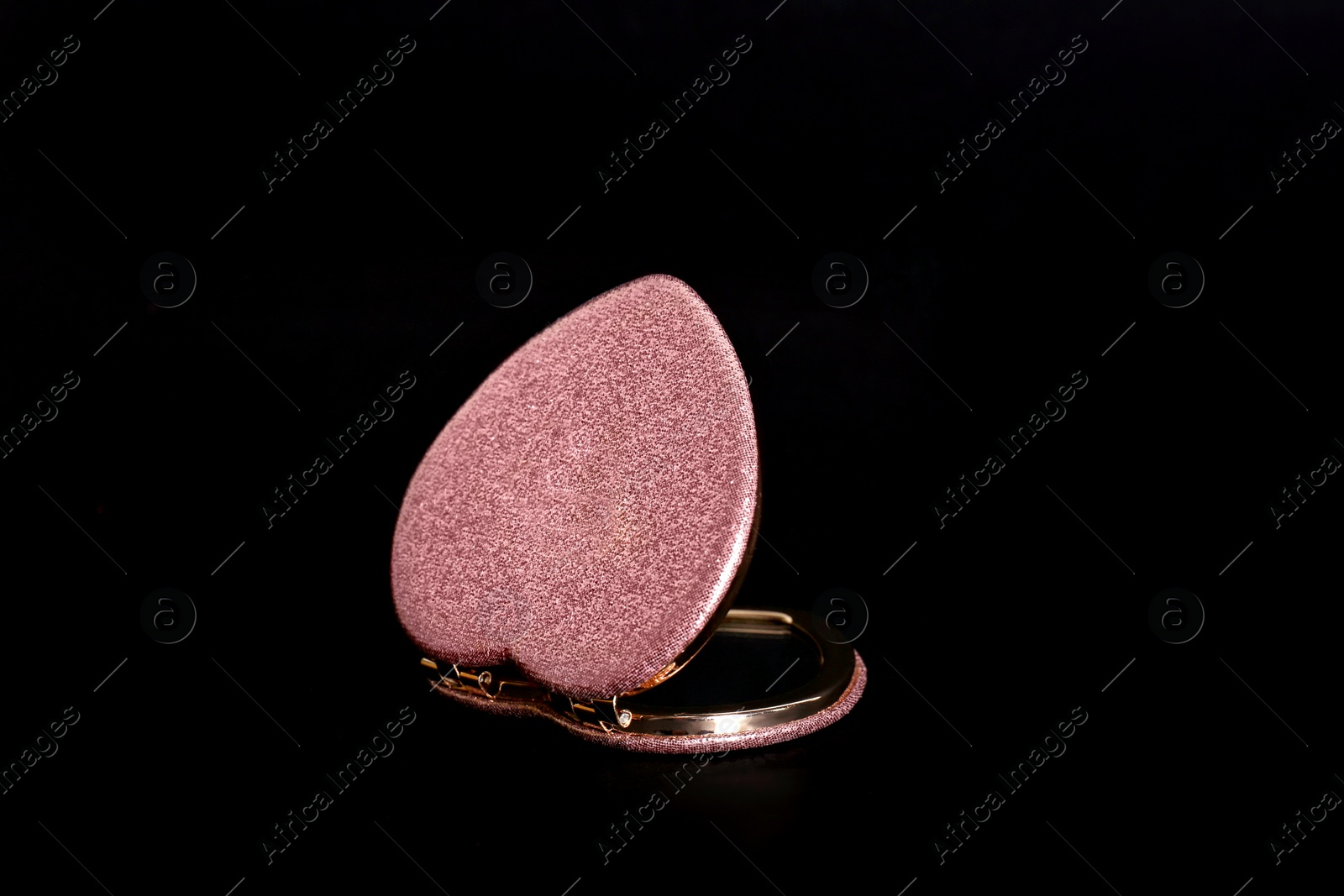 Photo of Heart shaped gold pocket mirror on black background