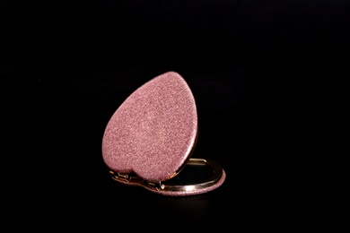 Photo of Heart shaped gold pocket mirror on black background