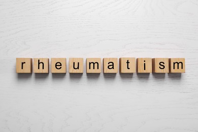 Word Rheumatism made of cubes on white wooden table, top view
