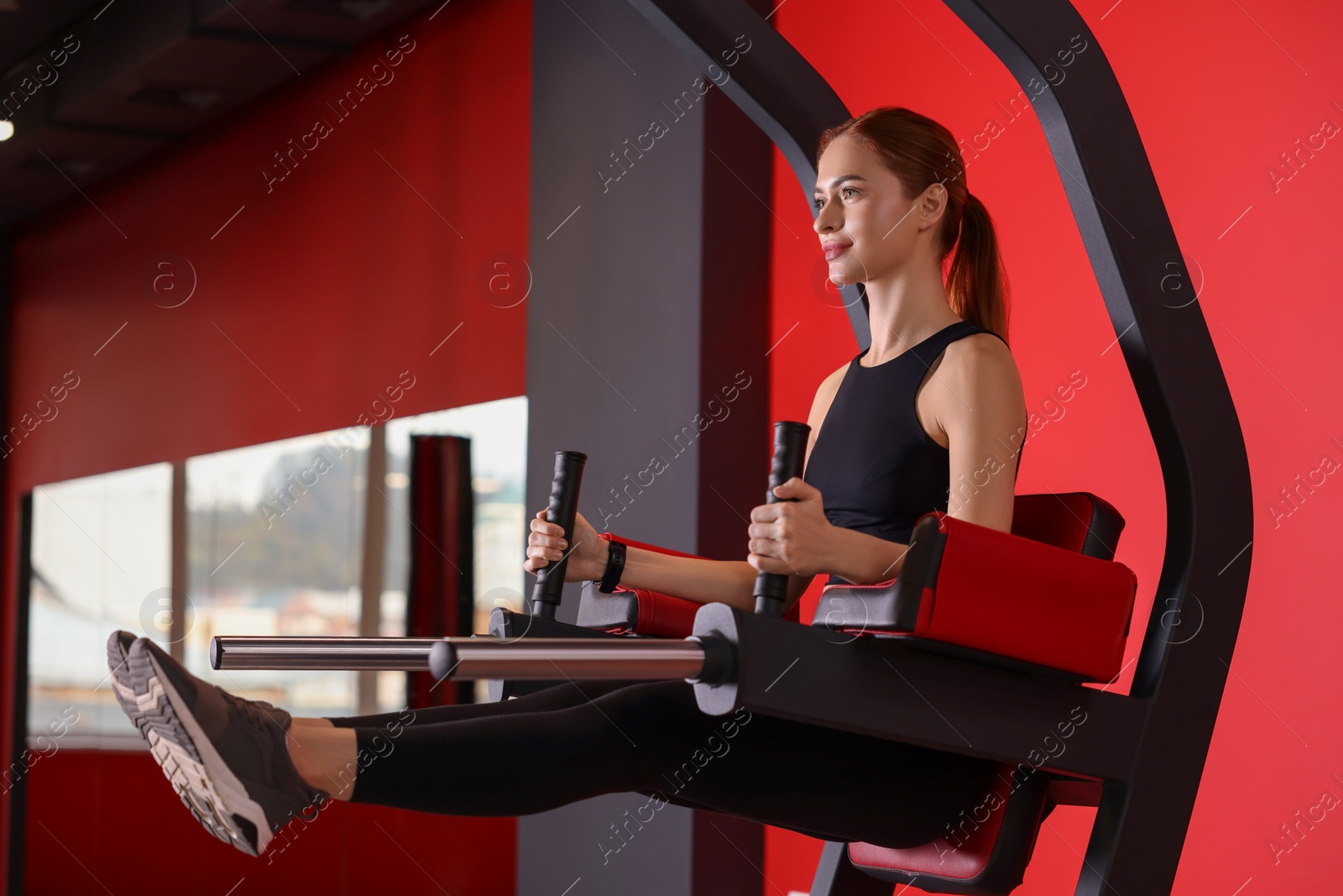 Photo of Athletic young woman training on power tower station in gym