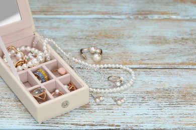 Photo of Jewelry box with many different accessories on rustic wooden table. Space for text