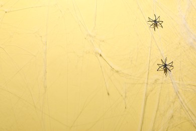 Photo of Cobweb and spiders on yellow background, top view
