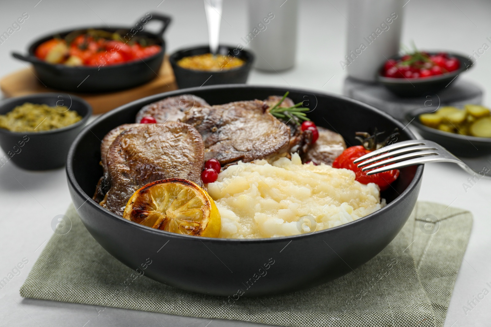 Photo of Tasty beef tongue pieces, berries, lemon, rosemary, tomato and mashed potatoes on white table, closeup