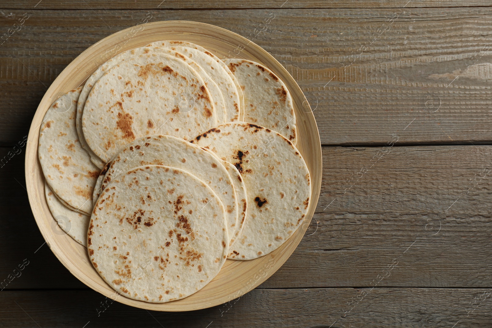 Photo of Many tasty homemade tortillas on wooden table, top view