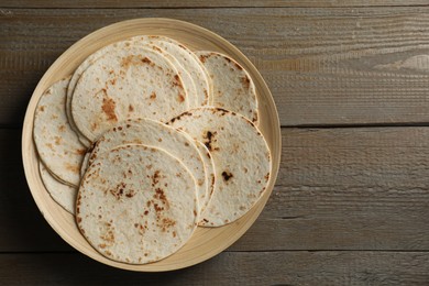 Photo of Many tasty homemade tortillas on wooden table, top view