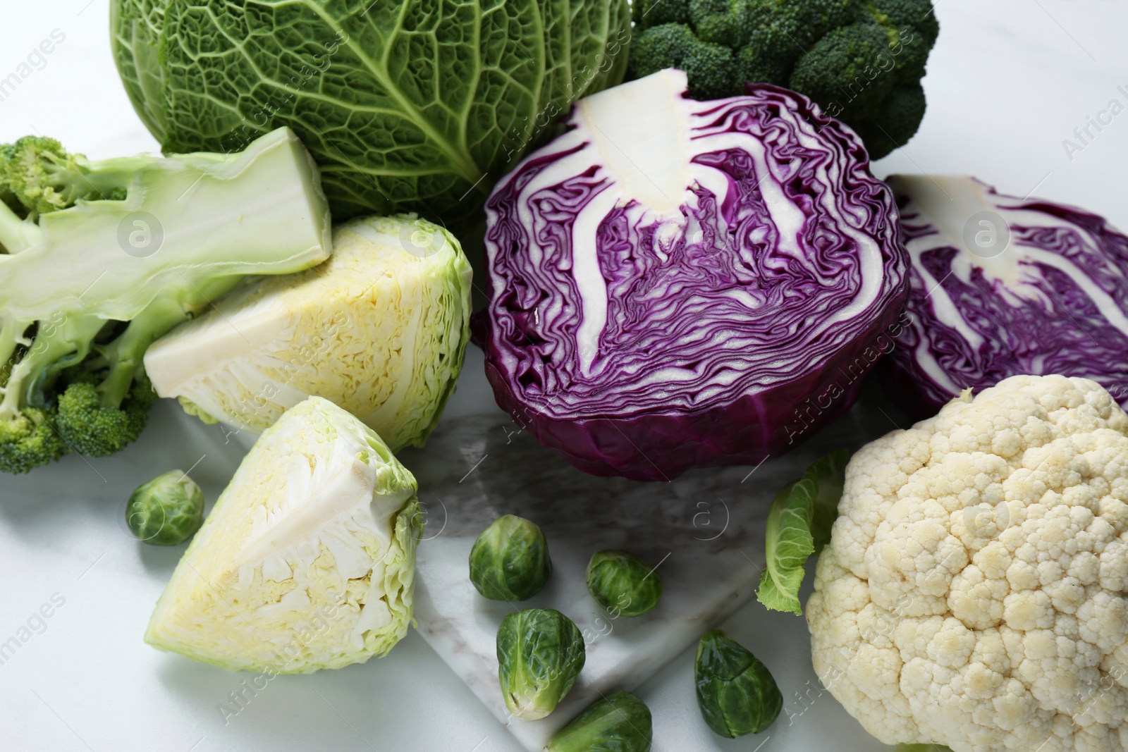 Photo of Many different types of cabbage on white table