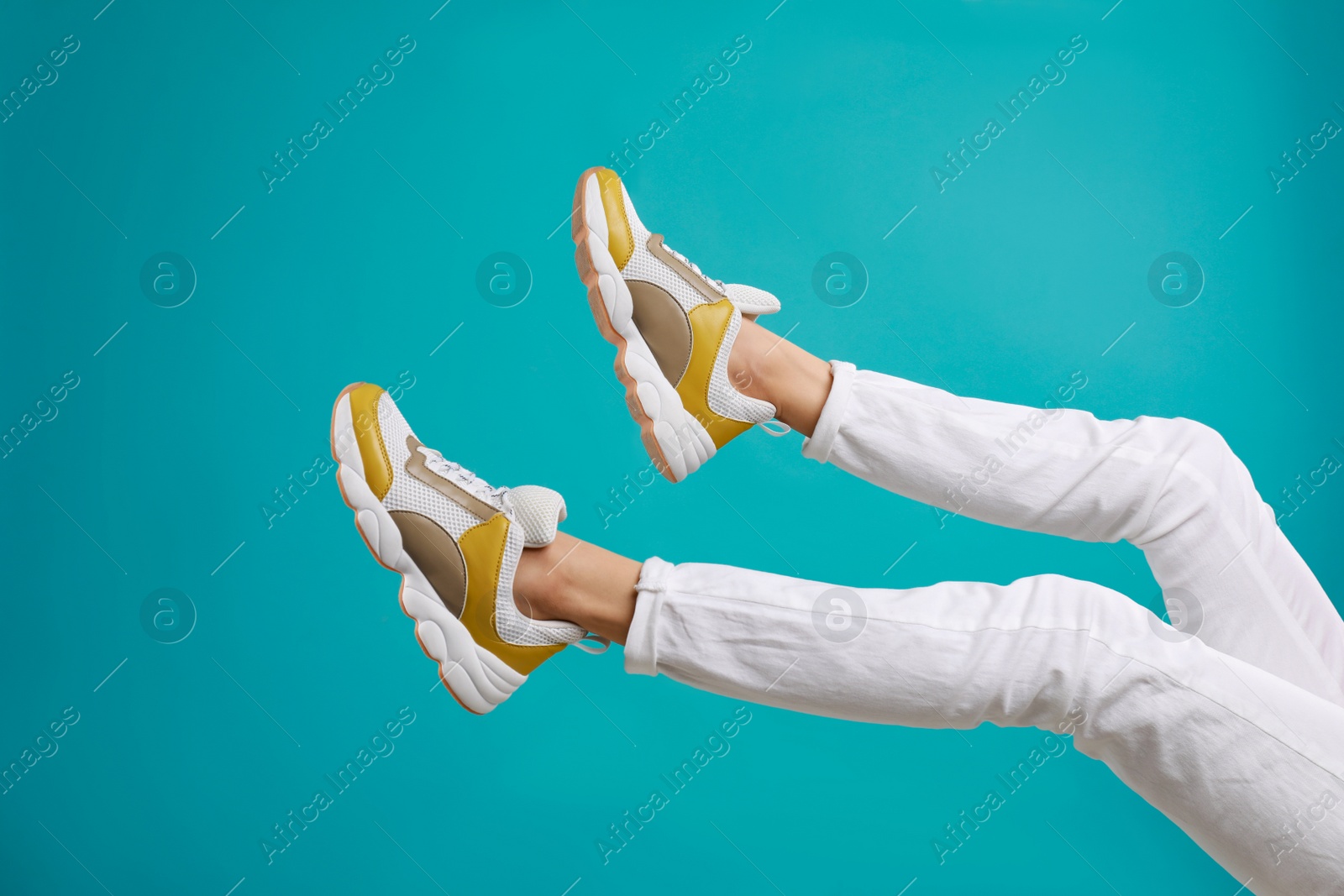 Photo of Woman in stylish sport shoes on light blue background