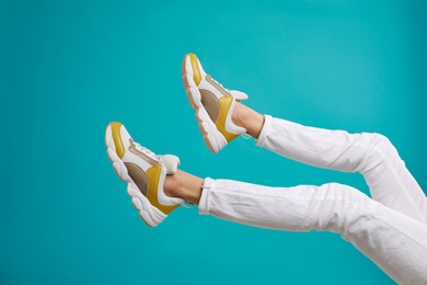 Photo of Woman in stylish sport shoes on light blue background