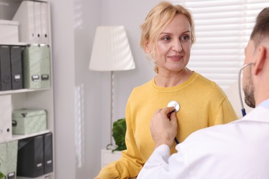 Photo of Doctor listening to patient's lungs with stethoscope in clinic