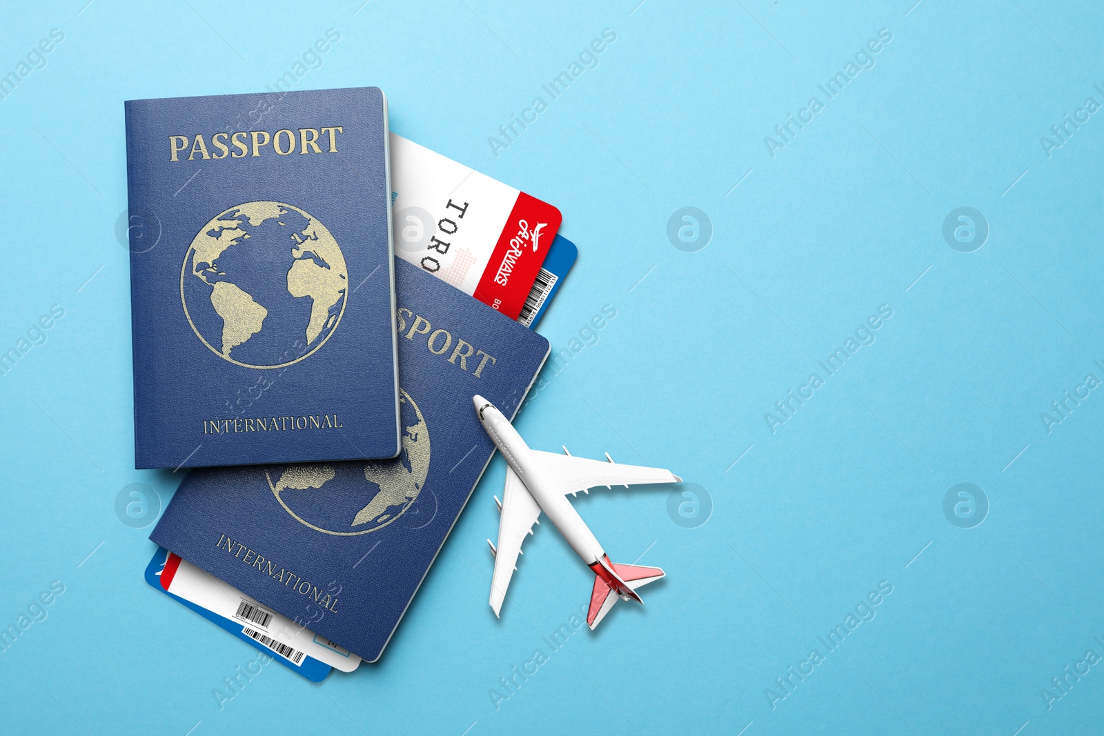 Image of International passports, boarding passes and airplane model on light blue background, flat lay. Space for text