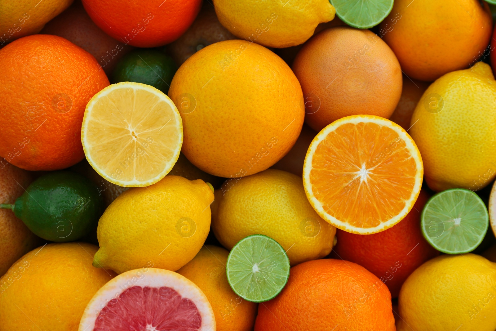 Photo of Many different whole and cut citrus fruits as background, top view