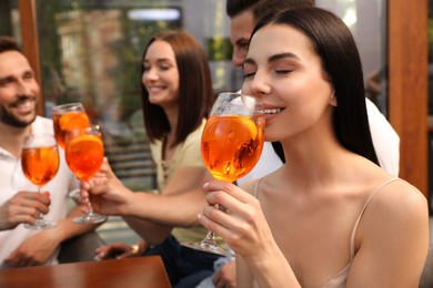 Photo of Friends spending time together, focus on young woman drinking Aperol spritz cocktail