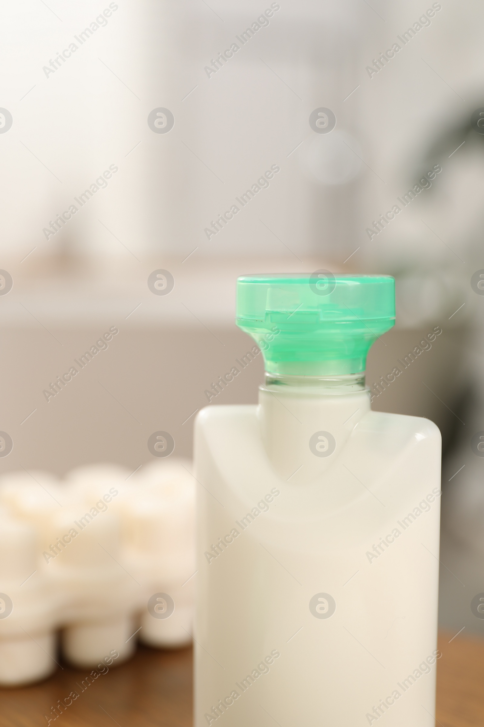 Photo of Mini bottle of cosmetic product on blurred background, closeup