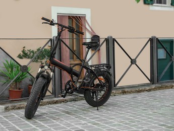 Photo of Modern electric bicycle near black metal fence outdoors