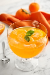 Photo of Delicious tangerine jelly on white marble table, closeup