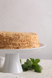 Photo of Delicious Napoleon cake and mint on table against light background, space for text