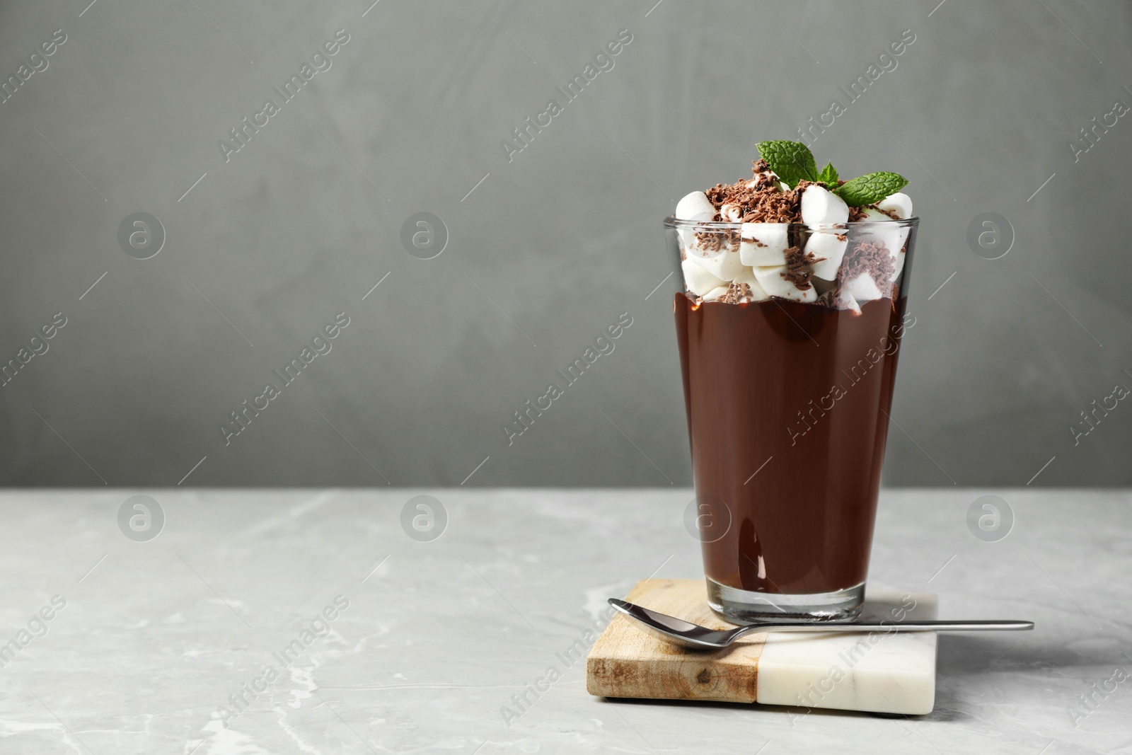 Photo of Glass of delicious hot chocolate with marshmallows and fresh mint on light grey marble table. Space for text