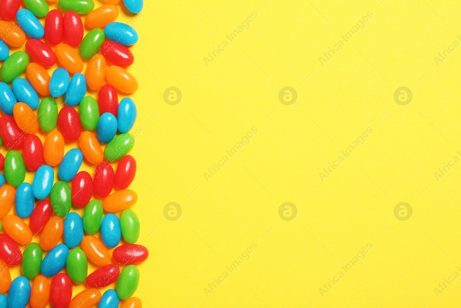 Photo of Delicious  bright jelly beans on color background, top view. Space for text