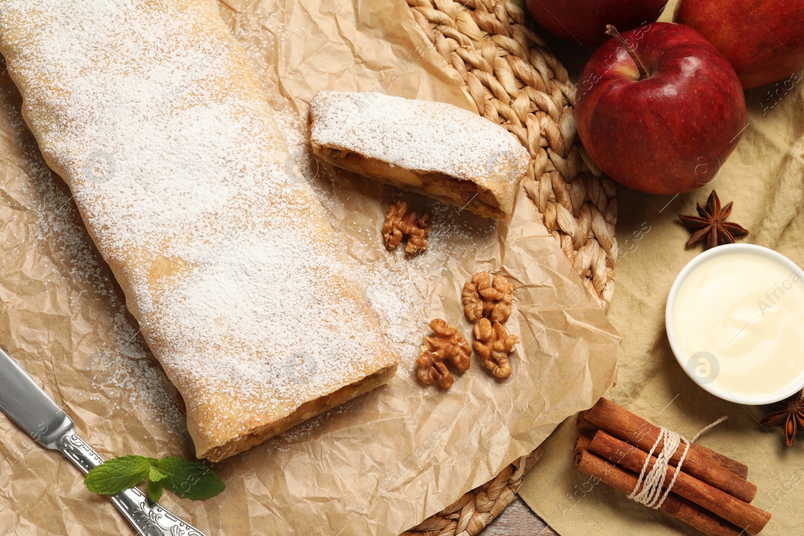 Photo of Delicious apple strudel with walnuts and powdered sugar on table, flat lay