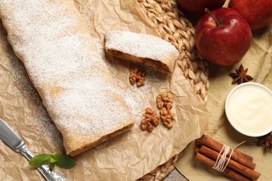 Delicious apple strudel with walnuts and powdered sugar on table, flat lay