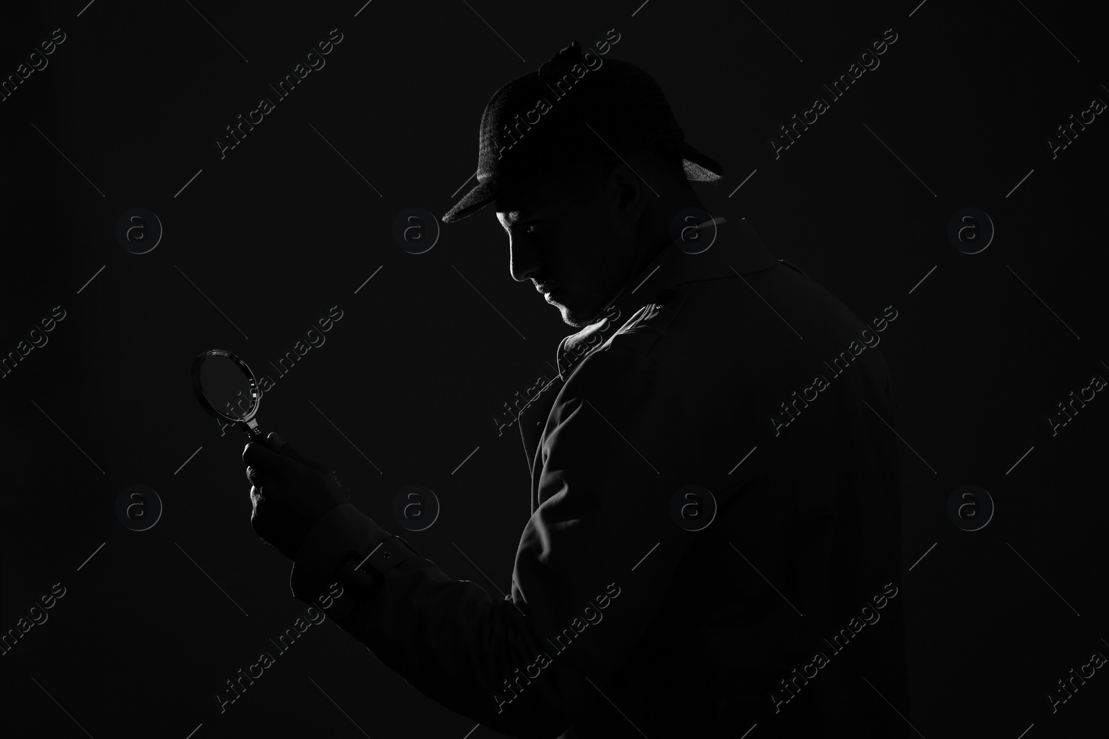 Photo of Old fashioned detective with magnifying glass on dark background, black and white effect