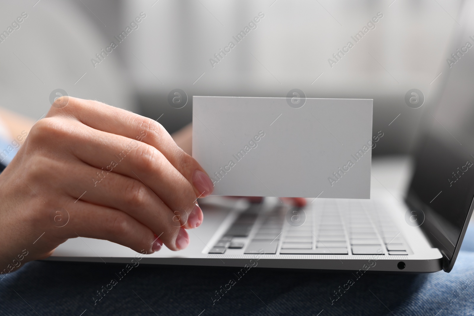 Photo of Woman with laptop holding blank business card, closeup. Space for text