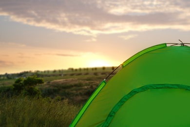 Modern camping tent in wilderness at sunset. Space for text