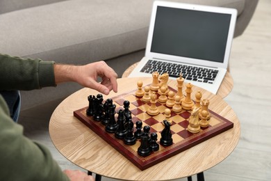 Photo of Man playing chess with partner through online video chat in living room, closeup