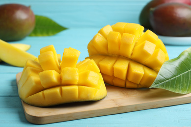 Photo of Cut fresh ripe mango on light blue wooden table